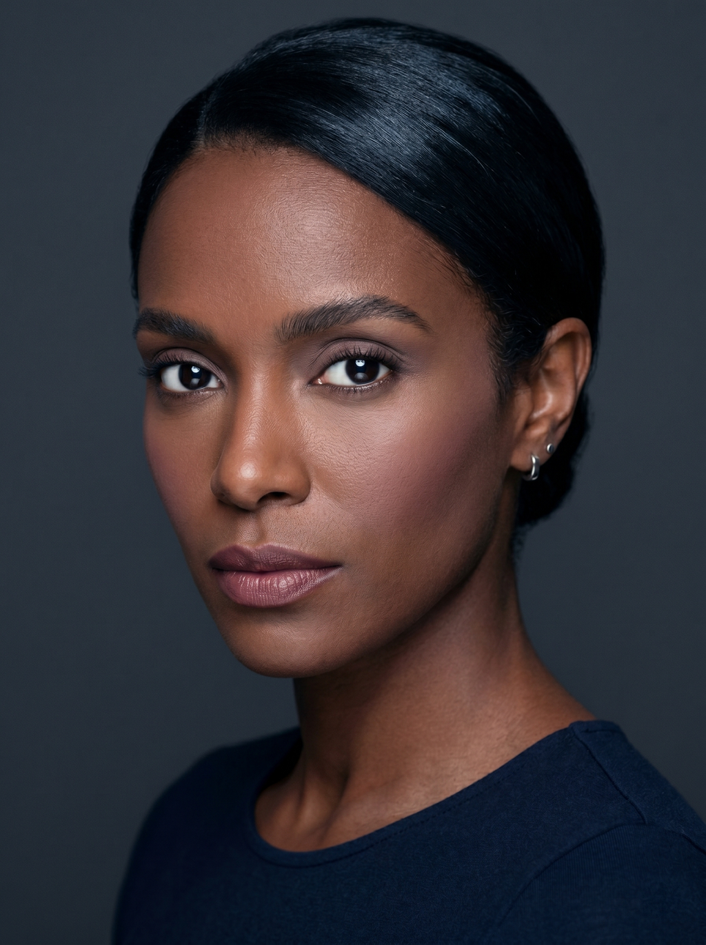 Dark Winter clean girl makeup on deep cool-toned skin: sheer cool taupe lids, soft blush, groomed brows, and a cool mauve-nude lip with sleekly pulled-back hair against a charcoal background