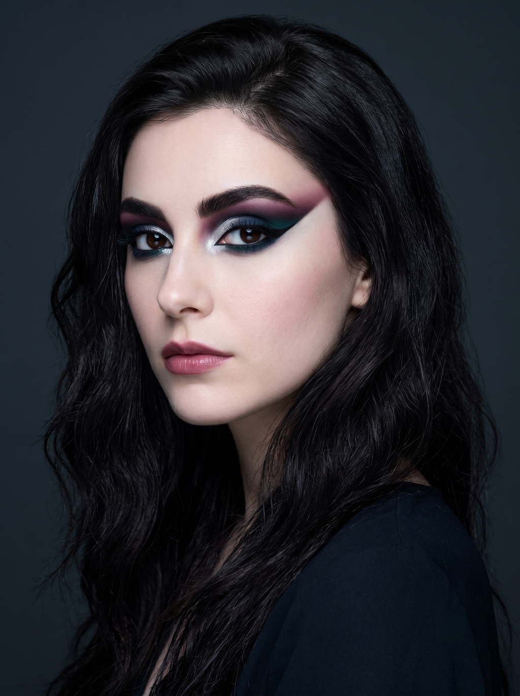 Dark Winter festival eye with a long graphic wing gradient from berry at the brow into navy through the crease into teal at the lash line, over a chrome-silver lid with a black tightline